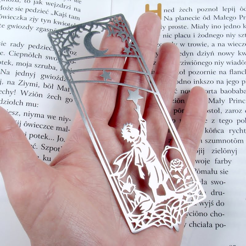 Metalowa zakładka z Małym Księciem pokazana na dłoni dla uzmysłowienia sobie jej rozmiarów